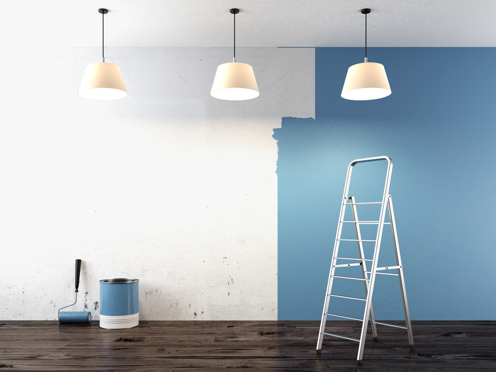 A room with three lights hanging from the ceiling that is in the process of being painted blue.